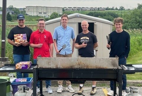 Five men standing at a BBQ