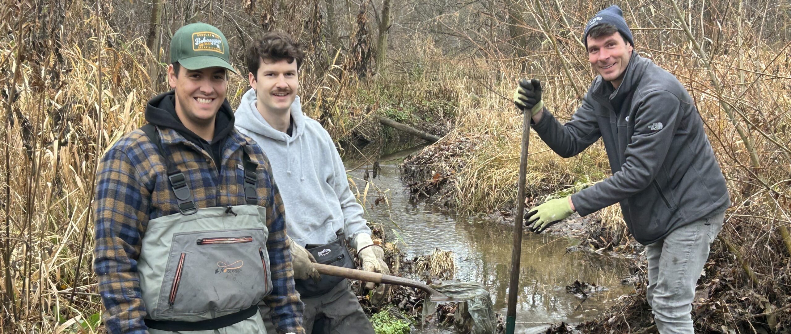 Three men digging in a stream outside